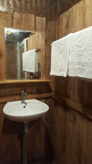 A wooden bathroom with a white sink and two white towels hanging on the wall.
