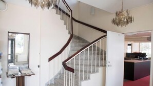 Una escalera de caracol con barandilla de madera y balaustradas blancas, que conduce a una habitación con alfombra roja y un escritorio con un ordenador.