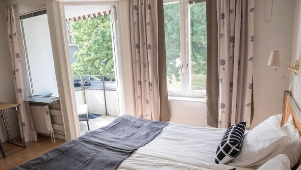 Un dormitorio con cama, escritorio y vista al exterior.