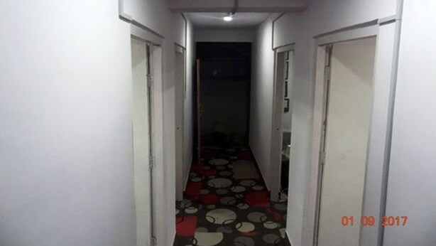 A narrow hallway with patterned flooring, white walls, and doors on both sides.