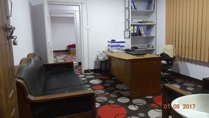 A small, compact room with a desk, chair, and a bookshelf.