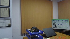 An office with a desk, a laptop, a blue storage unit, and framed certificates on the wall.