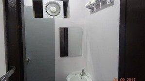A bathroom with a white sink, a mirror, and a hairdryer mounted on the wall.