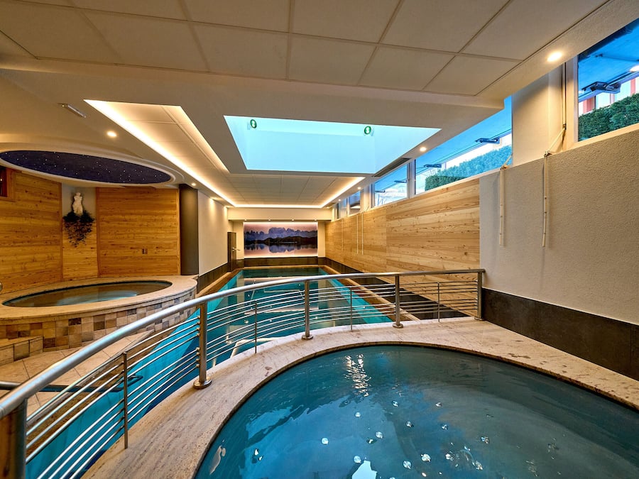 Een binnenzwembad, ligstoelen bij het zwembad