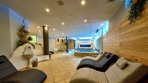 A spa area with massage chairs, a hot tub, and a view of the pool. - Hotel Cristina (Pinzolo)
