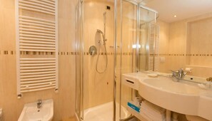 A modern bathroom with a glass-enclosed shower, a sink with a mirror, and a towel rack. - Hotel Cristina (Pinzolo)