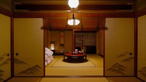 Una habitación tradicional japonesa con suelo de tatami, puerta corredera shoji y una mesa baja de tatami con una lámpara colgante.