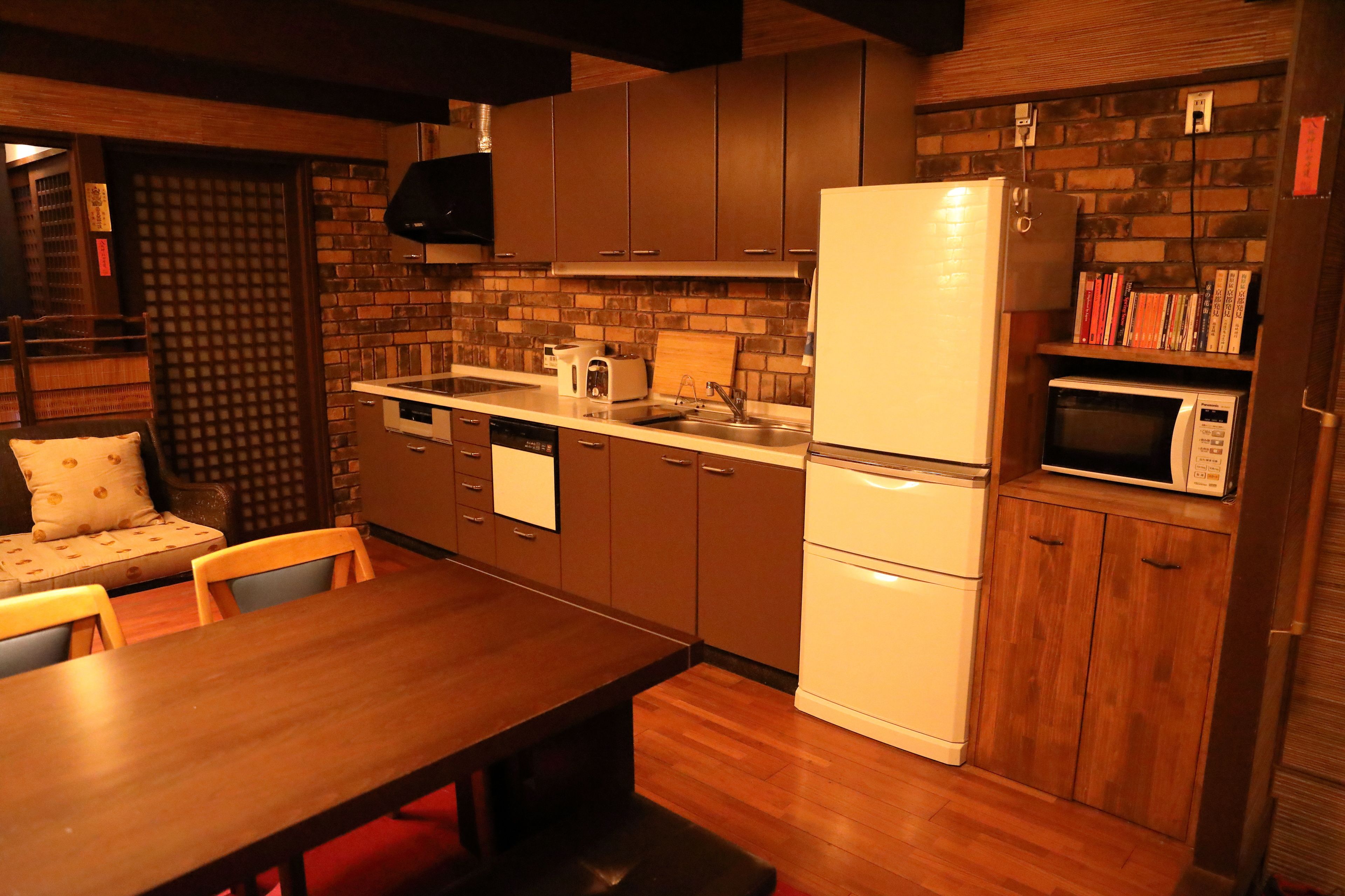 A compact kitchen with wooden cabinets, a refrigerator, a microwave, and a dining area with a table and chairs.