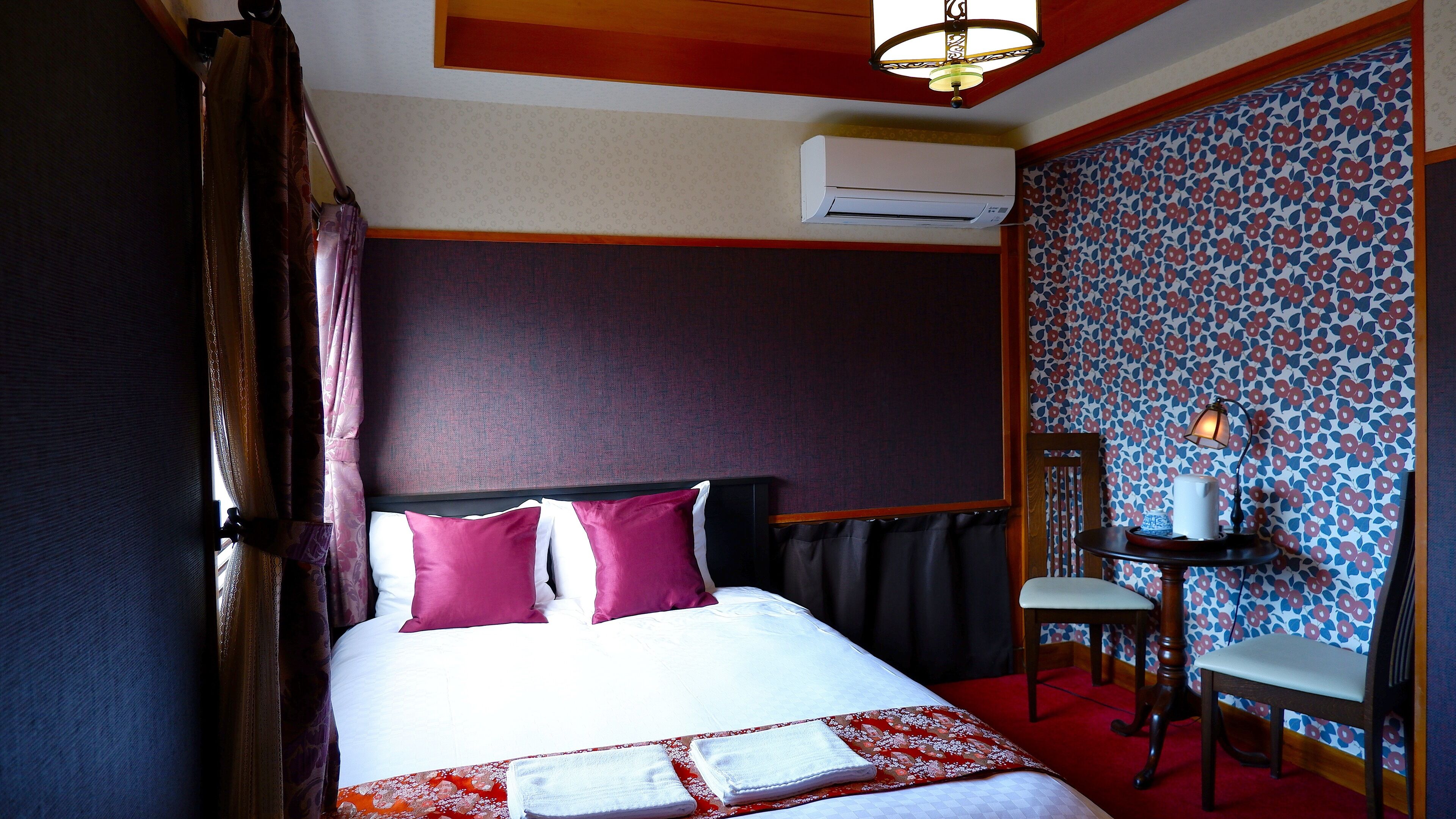 Habitación de hotel con cama, una silla, equipo de aire acondicionado y pared con diseño.