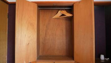A wooden wardrobe with a hanging rod and a small shelf.