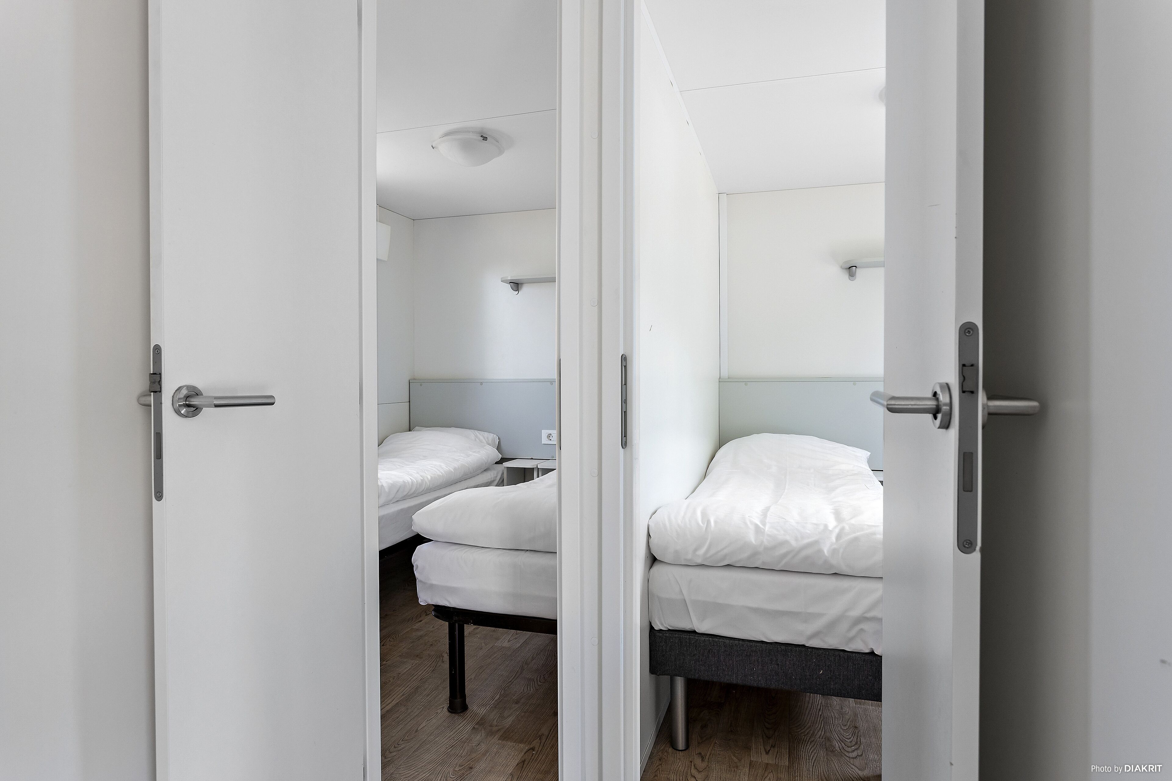 Ein Zimmer mit zwei Betten, jeweils mit weißer Bettwäsche und Holzboden.