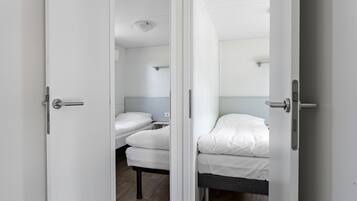 A room with two beds, each with white bedding and a wooden floor.