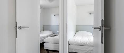 Ein Zimmer mit zwei Betten, jeweils mit weißer Bettwäsche und Holzboden.