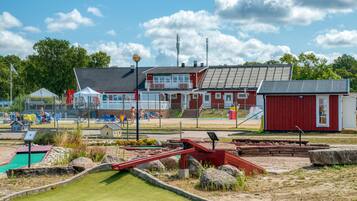A red building with a sloped roof, a small pool, and a playground area with slides and swings.