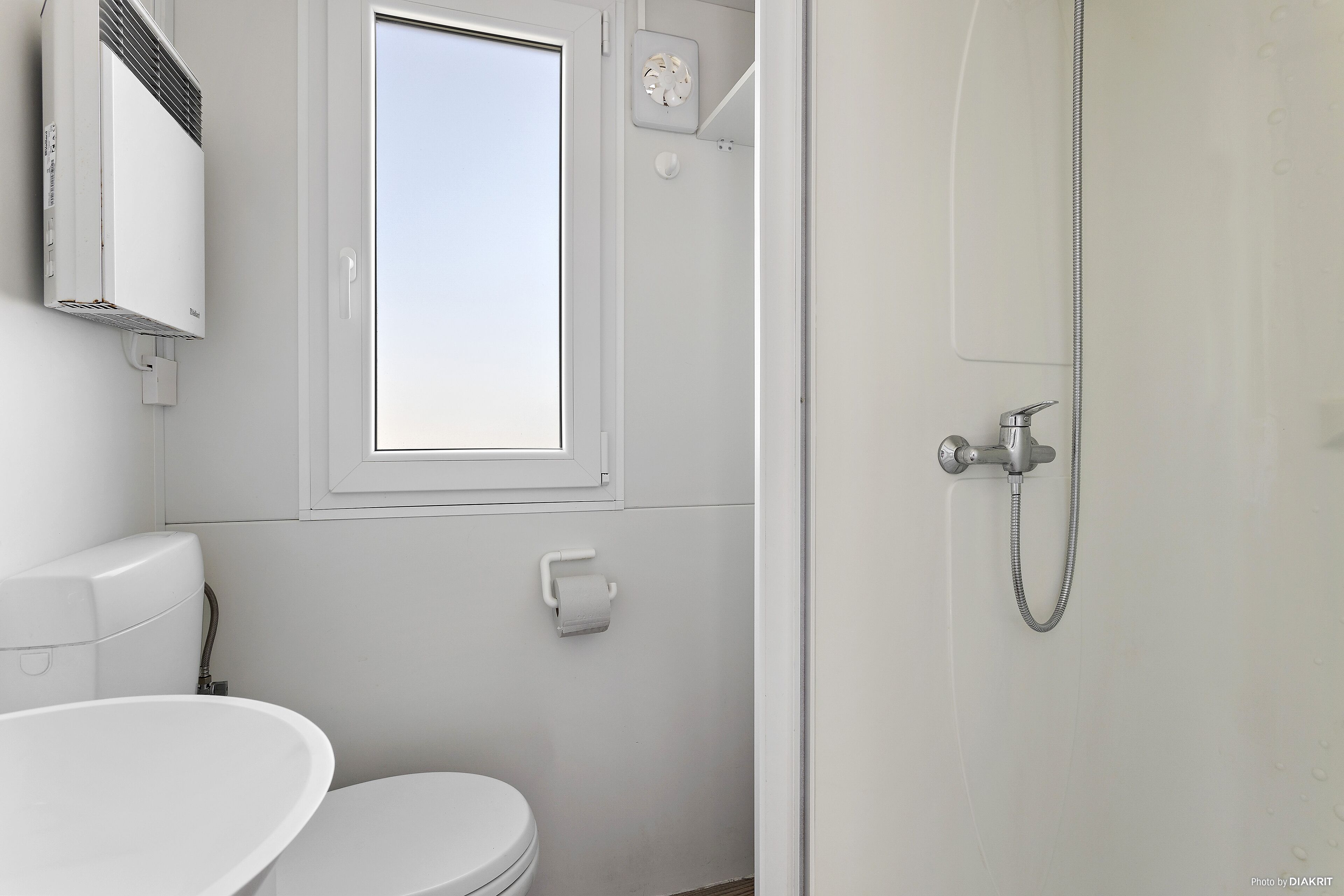 A modern bathroom with a toilet, a sink, a shower, and a window.