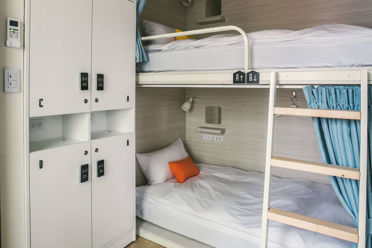 A bunk bed room with a wardrobe, a desk, and a hanging rack.