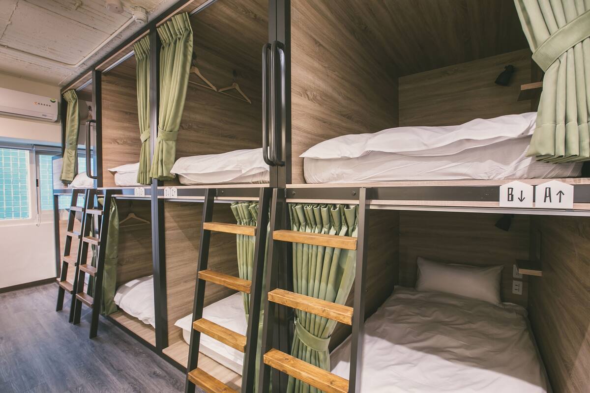 A bunk bed room with wooden walls, a ladder, and a window with a view.