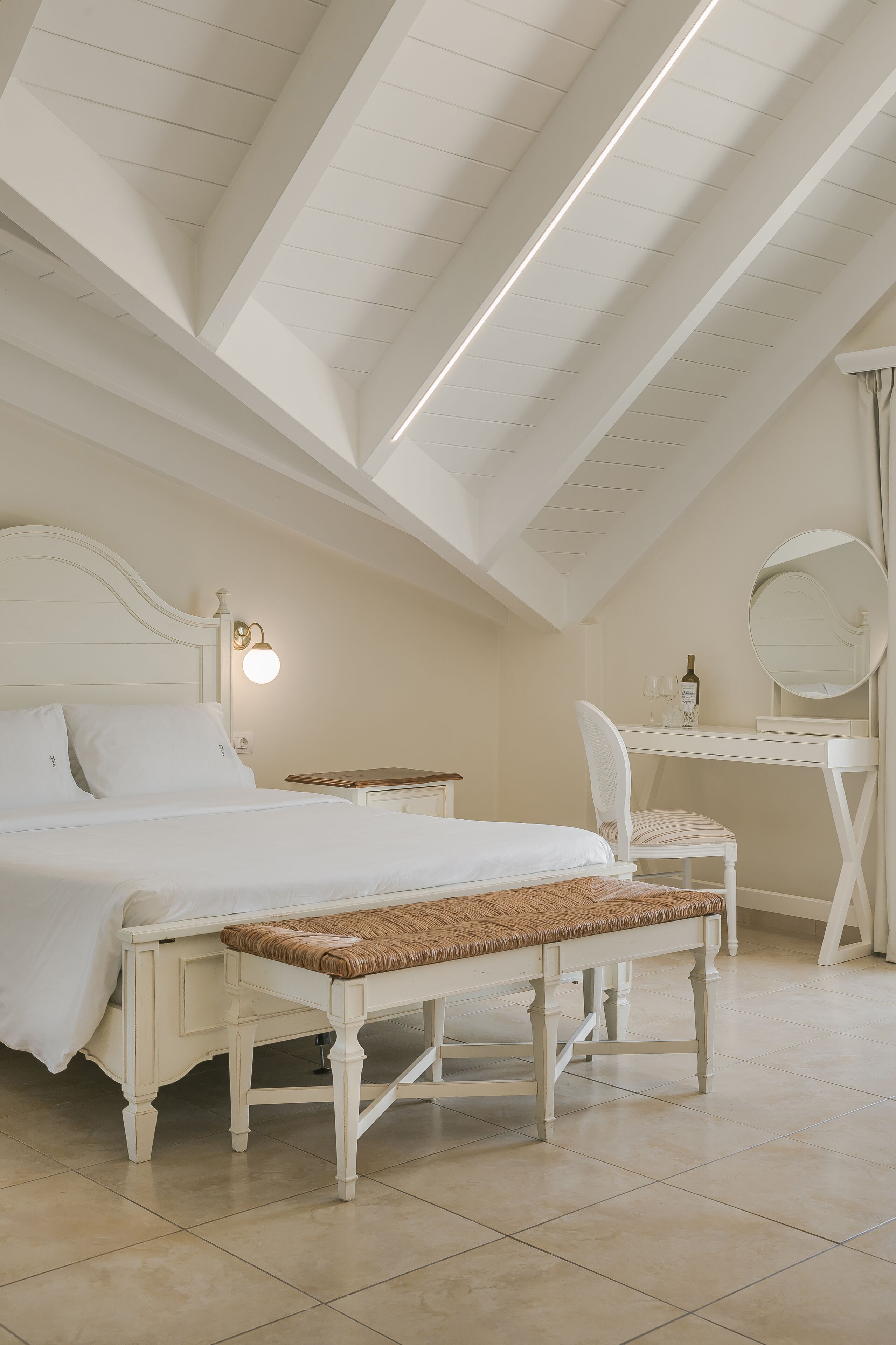 Un dormitorio con cama, mesita de noche, banco, escritorio, silla y espejo.