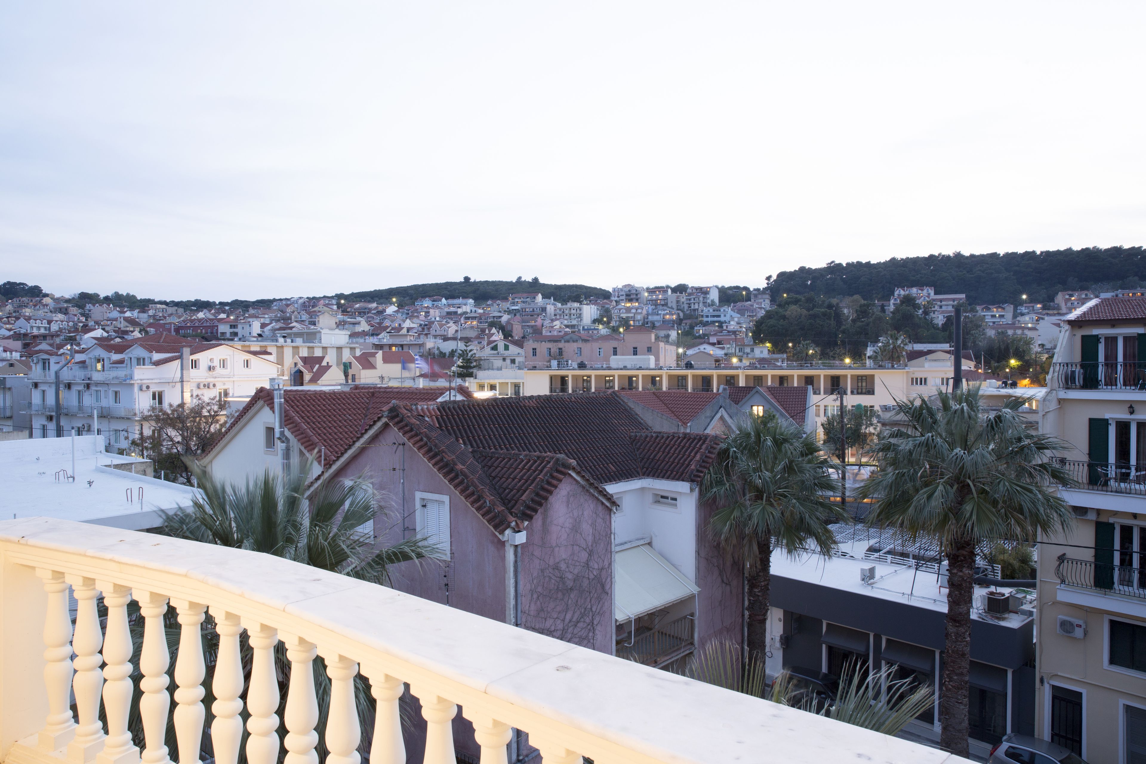 A residential area with buildings, some with red-tiled roofs, and palm trees.