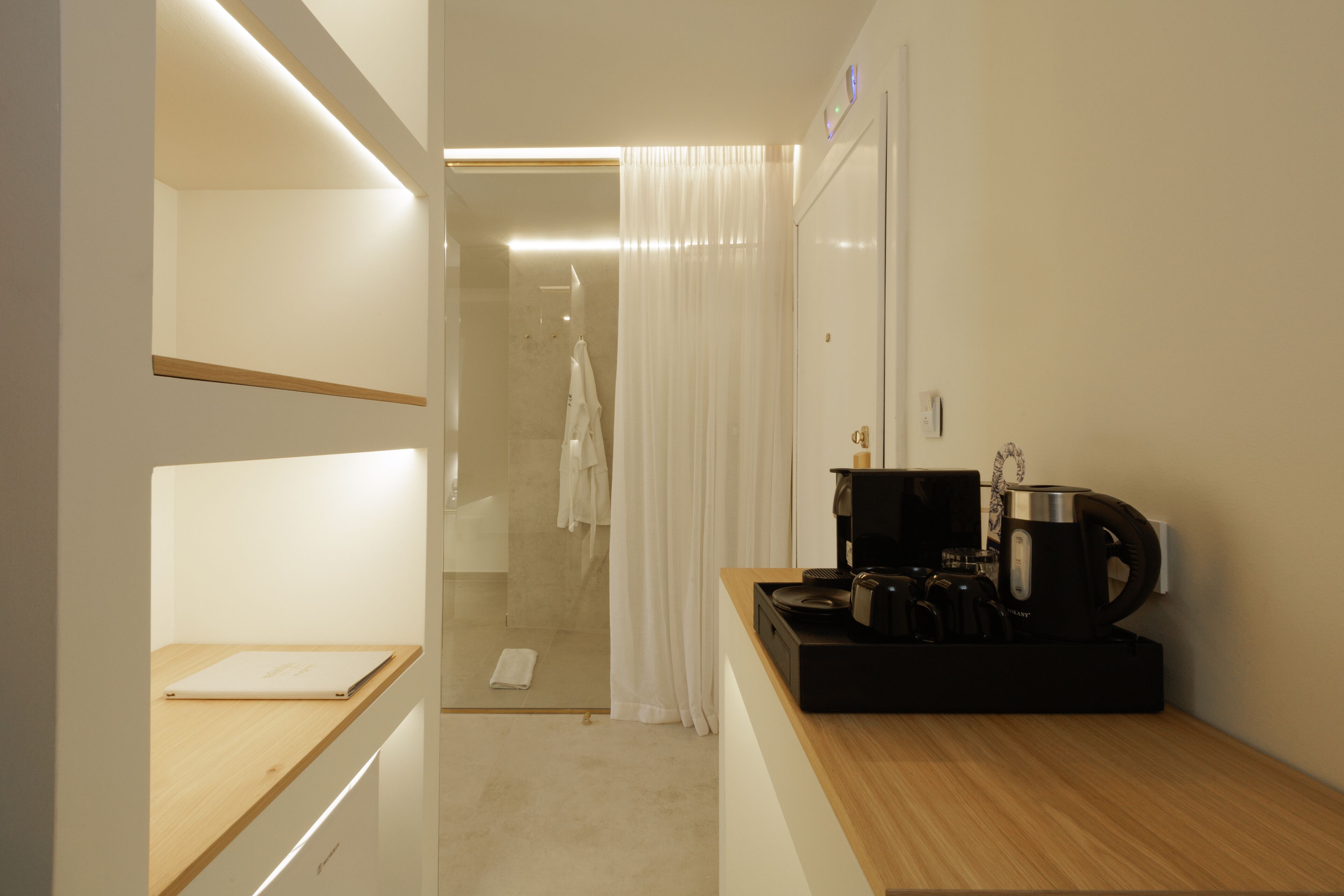 A modern bathroom with a shower, a toilet, and a sink area with a coffee maker and kettle.