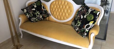 A sofa with floral cushions in a modern bathroom with a glass shower enclosure.