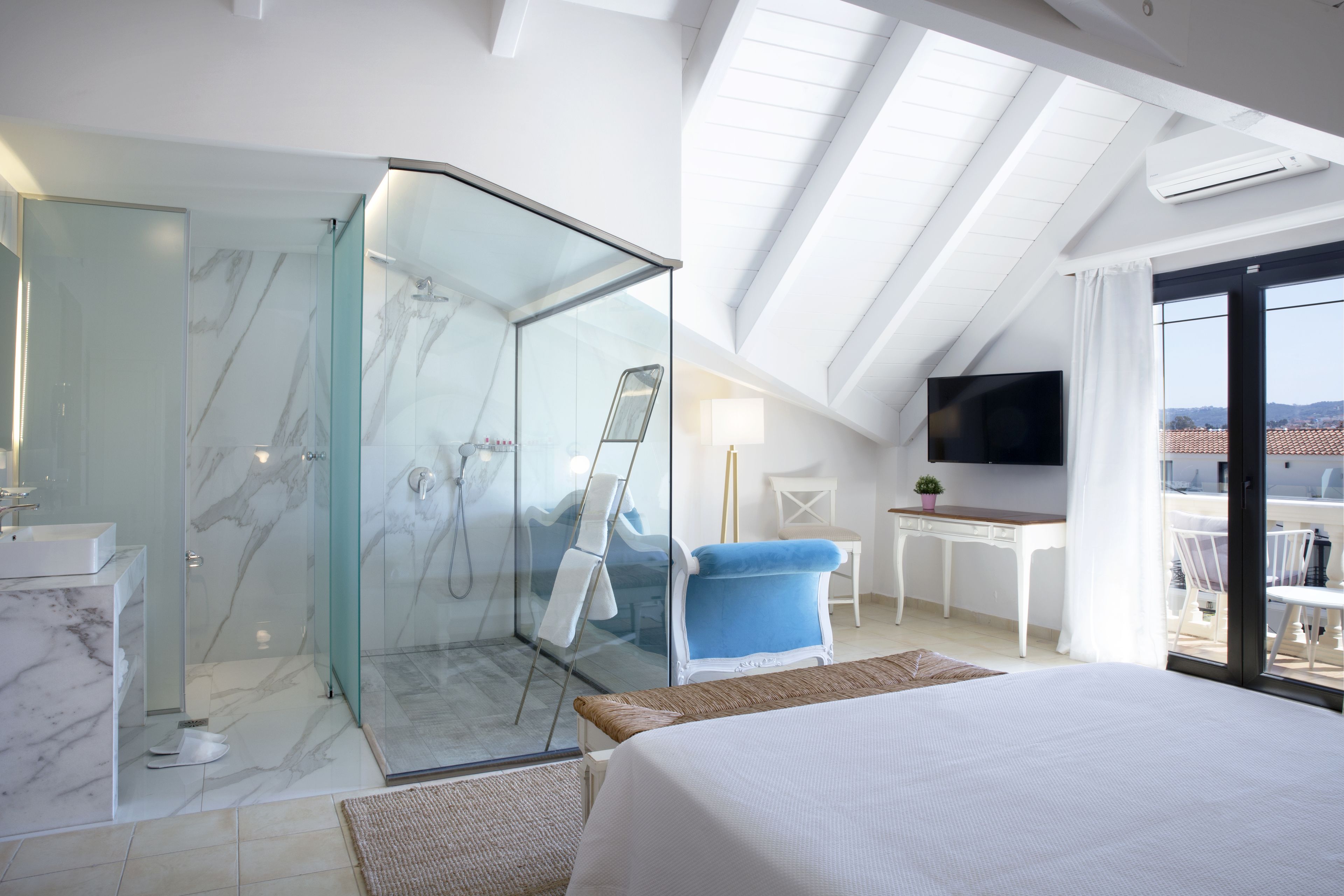 Une chambre d’hôtel moderne dotée d’une douche en verre, d’un lit, d’un bureau et d’une télévision.