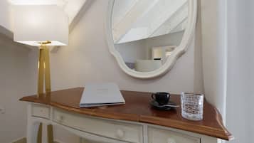 A wooden vanity with a mirror, a lamp, a cup, and a glass.