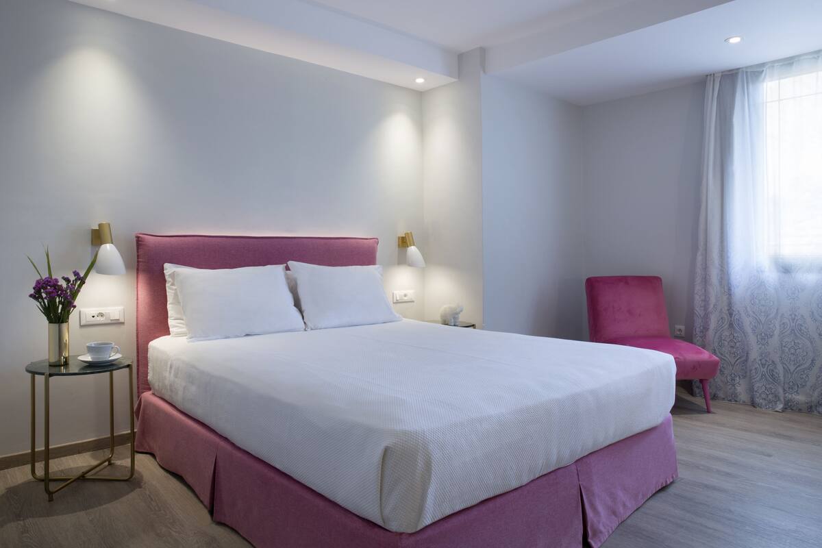 A neatly arranged bedroom with a large bed, bedside tables, and a chair.