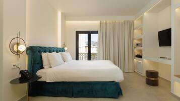 A modern hotel room with a large bed, a bedside table with a phone, a TV on the wall, and a view of the outdoors through a door.
