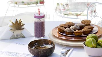 A table with a plate of muffins, a jar with a straw, a decorative item, a bowl, and a menu.
