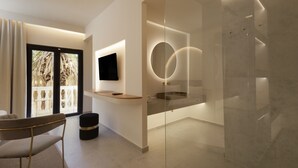 Un baño moderno con cabina de ducha de vidrio, televisor montado y diseño minimalista.