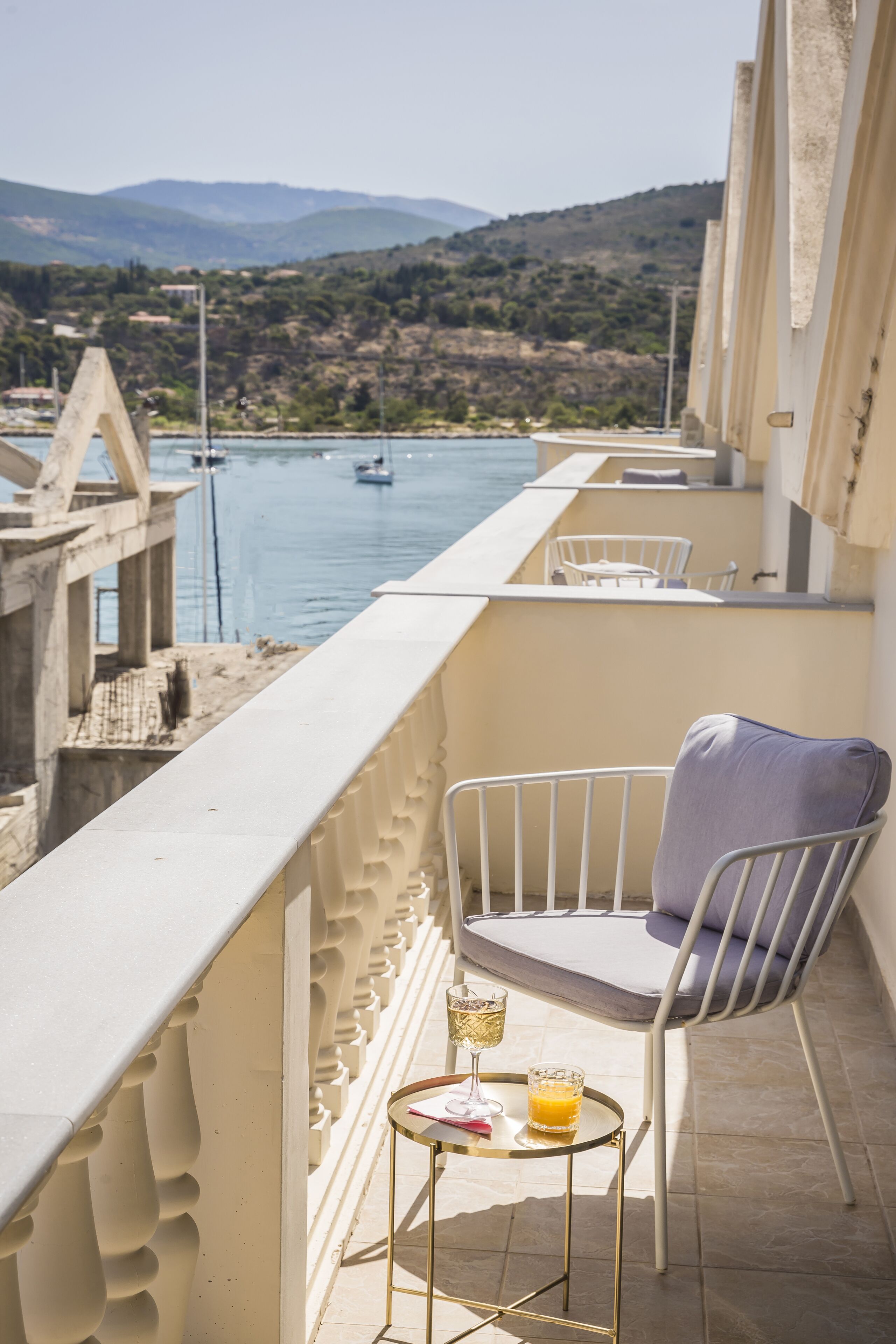 Ein Balkon mit Blick auf ein Gewässer, ein Stuhl und ein kleiner Tisch mit einem Glas Orangensaft.