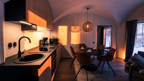 A modern kitchen with a built-in oven, a sink, and a dining area with a table and chairs.