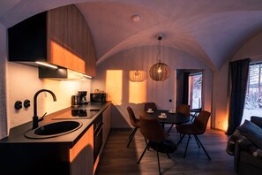 A modern kitchen with a built-in oven, a sink, and a dining area with a table and chairs.