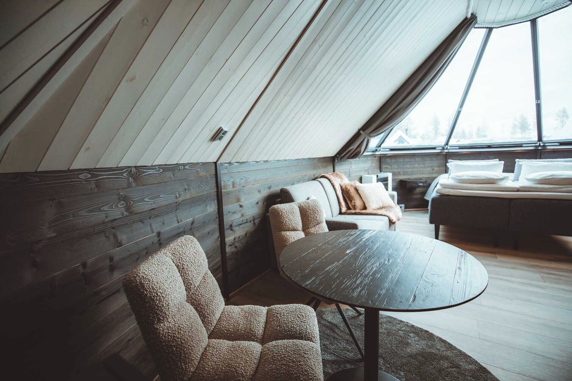 Un interior acogedor con techo de madera, una mesa redonda, un sofá y una cama.