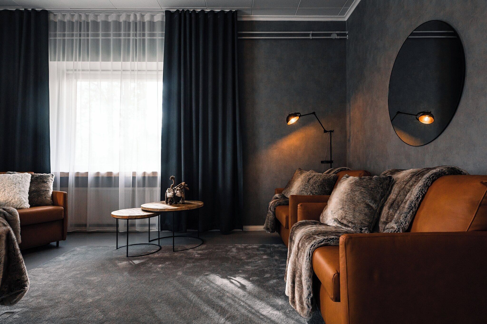 A modern living room with a sofa, a round coffee table, and a wall-mounted lamp.