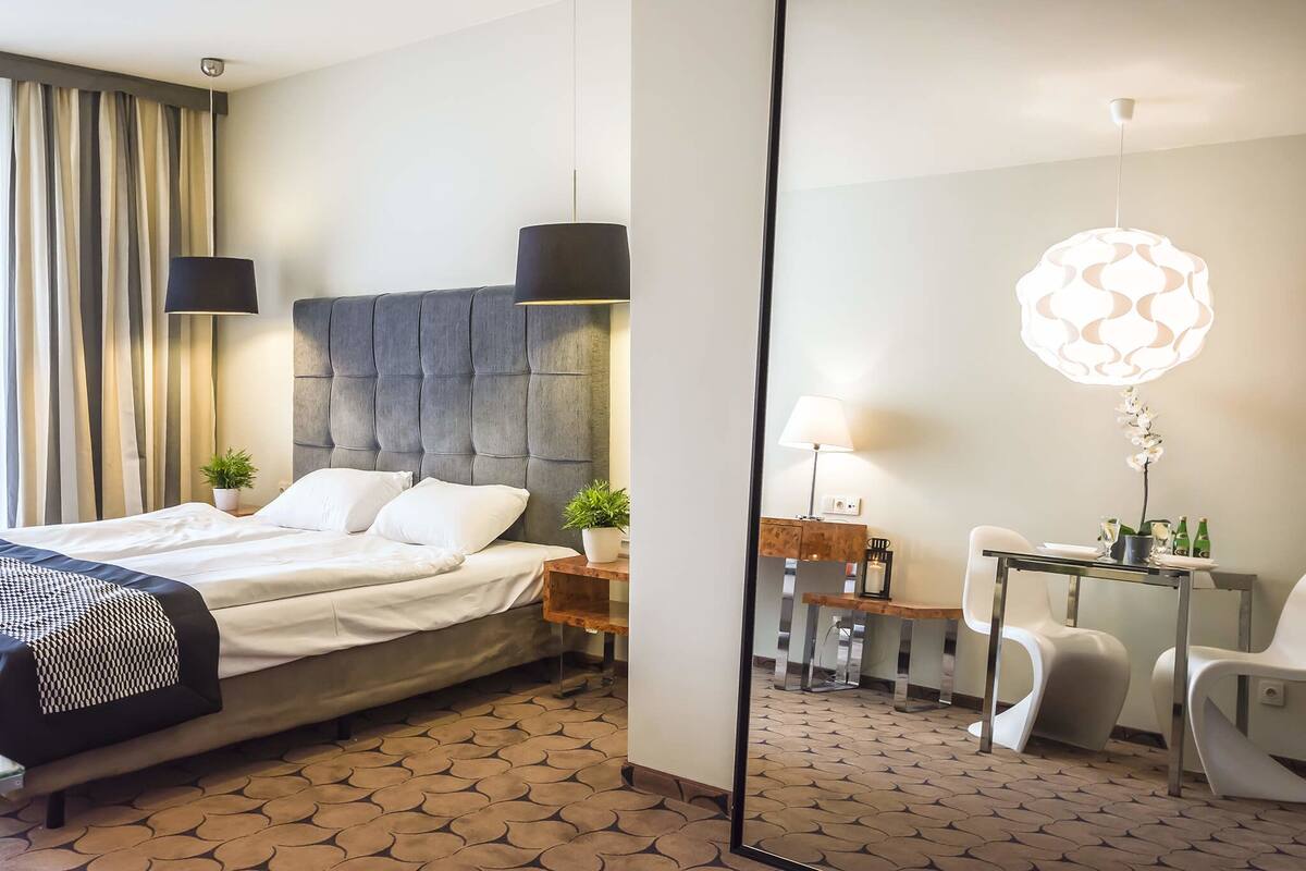 Een hotelkamer met een groot bed, een bureau, een stoel en een spiegel.
