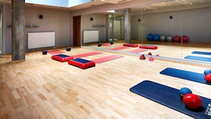 Une salle de sport dotée de planchers en bois, de tapis de sol et de divers équipements de remise en forme.