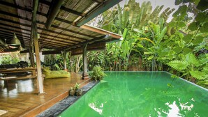 Ein Pool mit Holzterrasse und überdachtem Bereich mit Metalldach.