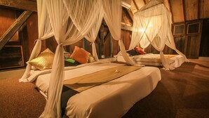Ein Zimmer mit einem Bett unter einem Baldachin, einer Holzbalkendecke und einem Fenster.