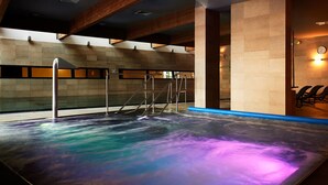 Une piscine intérieure moderne avec un mur en verre, des poutres en bois et une horloge au mur.