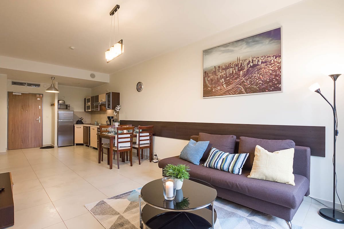 Eine moderne Wohnung mit Essbereich, Küche und Wohnzimmer mit Sofa und Couchtisch.