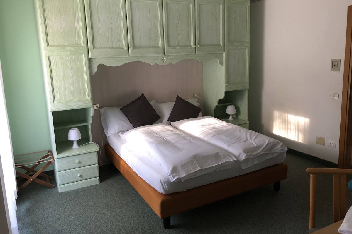 A bedroom with a bed, nightstands, and a wardrobe.