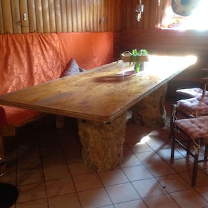 A wooden table with a stone base, a cushioned bench, and two chairs with cushions. - Hotel El Paso (Fai della Paganella)