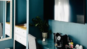A modern bathroom with teal walls, a white vanity, a mirror, a sink, a shower, and a toilet. - In Trastevere house (Rome)