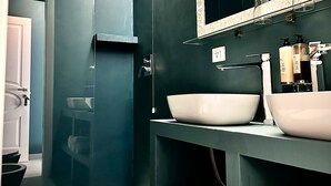 A modern bathroom with a large mirror, two sinks, and a shower area. - In Trastevere house (Rome)