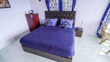 Ein Schlafzimmer mit einem großen Bett, einem Kleiderschrank, einem Nachttisch und einem Sessel.