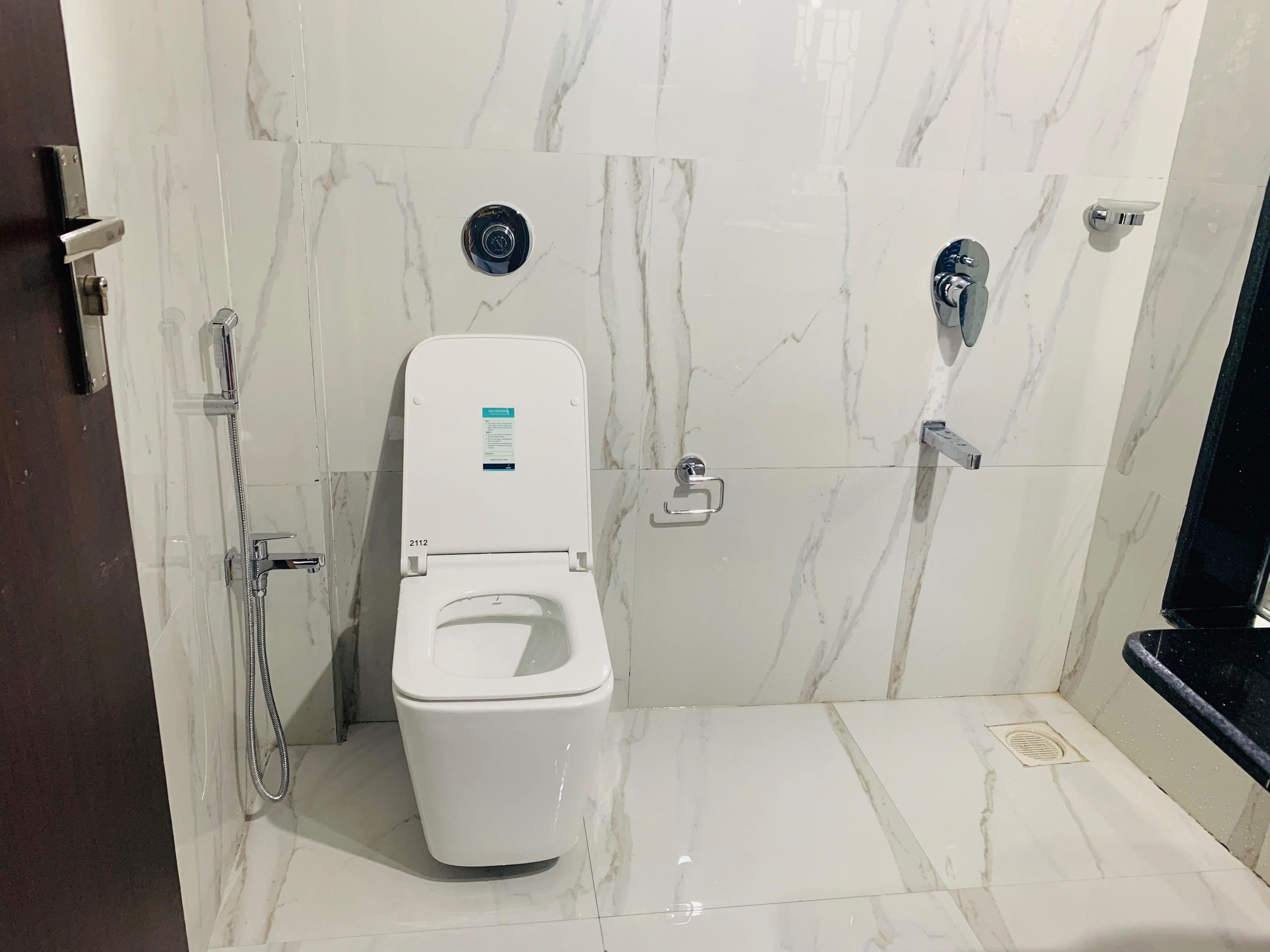 Een moderne badkamer met een wit toilet, een douchetoilet en een douche.
