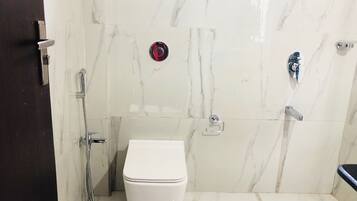 A bathroom with a white toilet, a shower, and a sink.