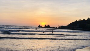 Une plage avec des vagues et un coucher de soleil.